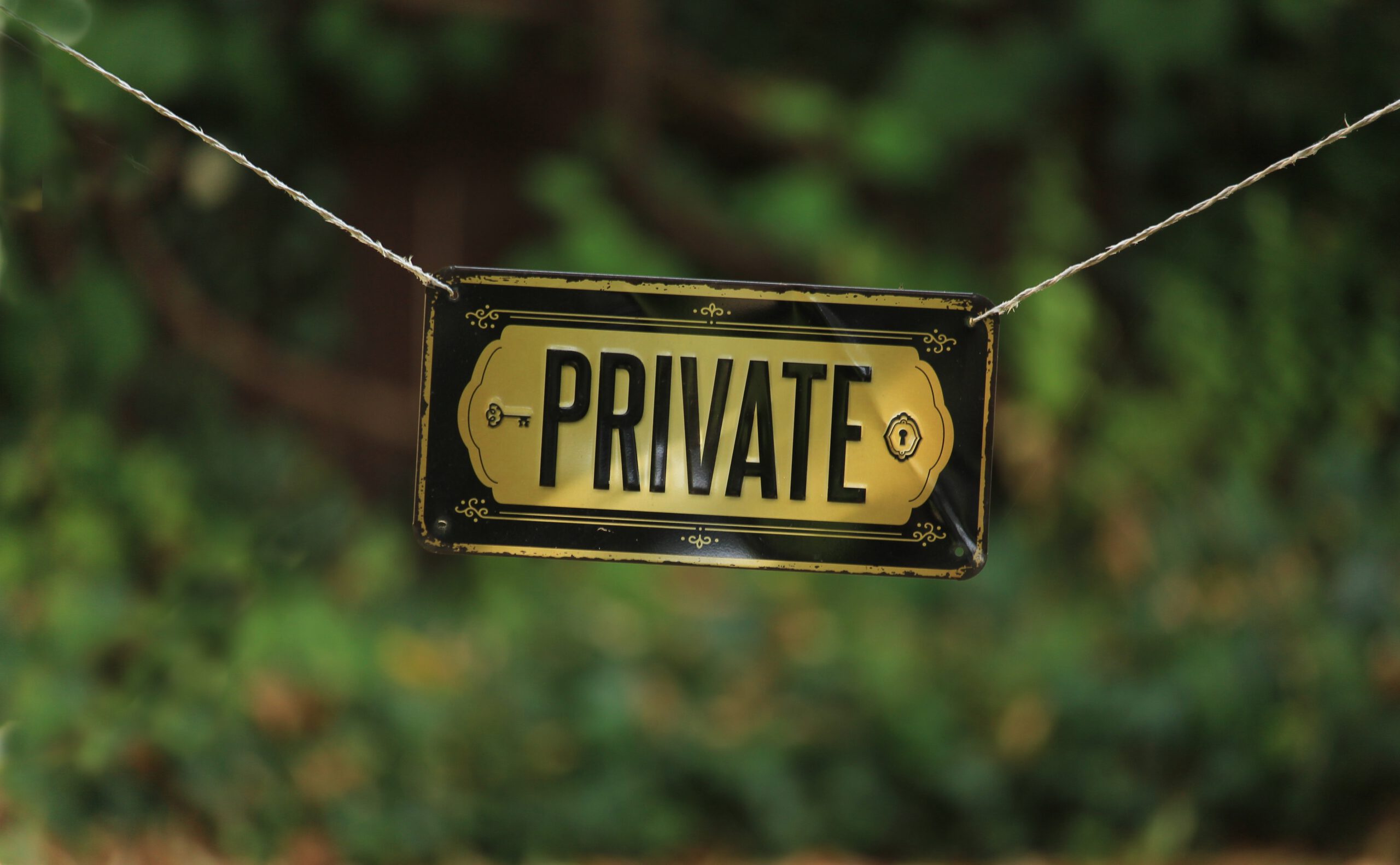Schild mit der Aufschrift PRIVATE an einer Schnur vor grünem Hintergrund